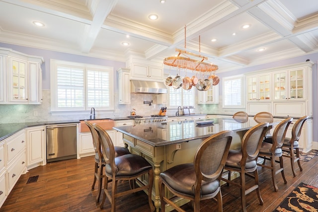 kitchen with under cabinet range hood, a breakfast bar, coffered ceiling, and dishwasher