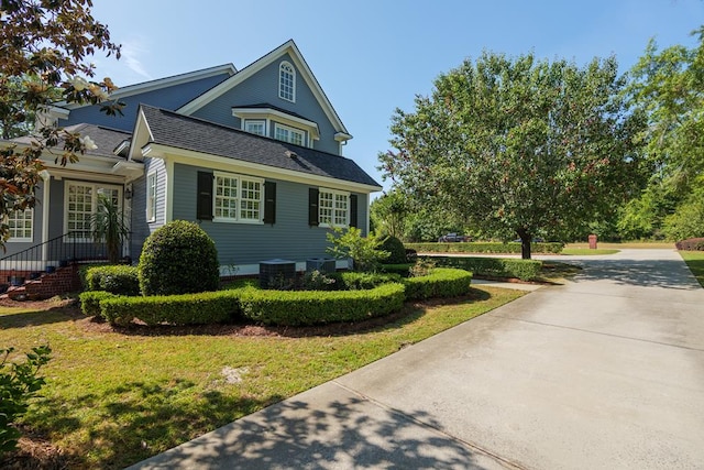 view of home's exterior with concrete driveway, a shingled roof, cooling unit, and a lawn