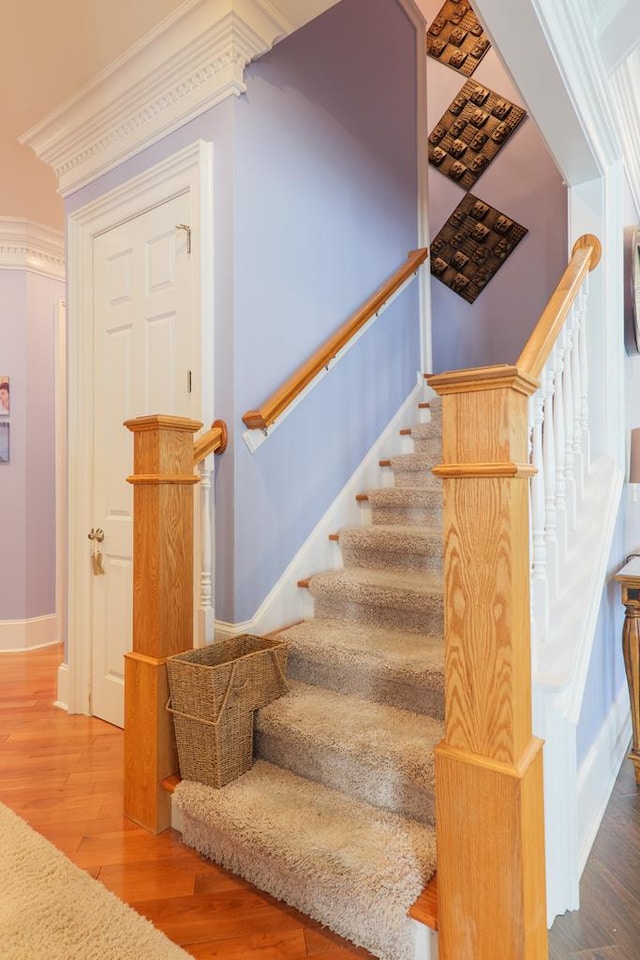 stairs with ornamental molding, baseboards, and wood finished floors