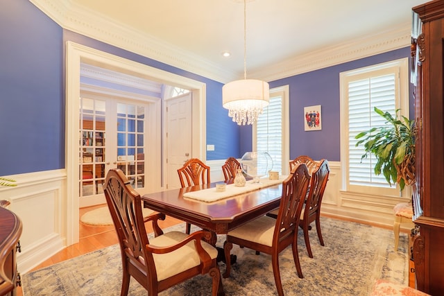 dining space featuring a wainscoted wall, ornamental molding, and light wood-type flooring