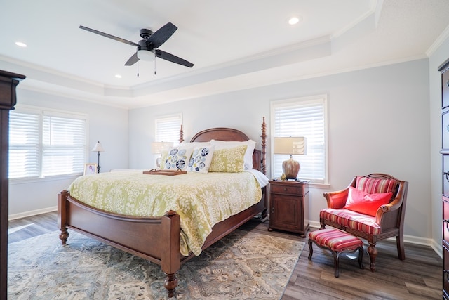 bedroom featuring recessed lighting, wood finished floors, baseboards, ornamental molding, and a tray ceiling