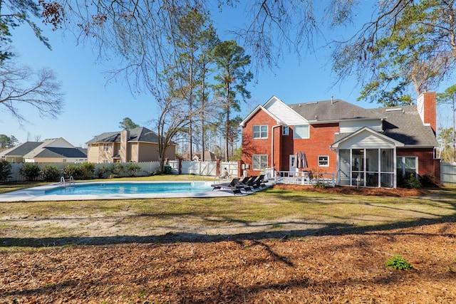 view of pool with a sunroom, a fenced in pool, fence, and a lawn