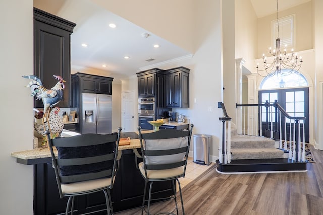 kitchen with a breakfast bar, a peninsula, ornamental molding, and stainless steel appliances