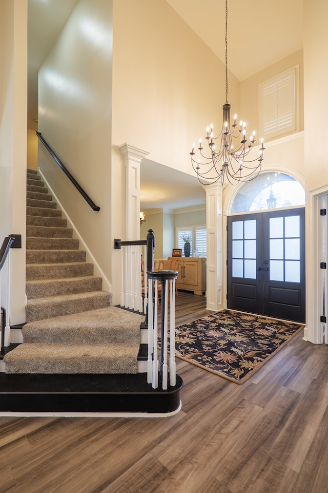 foyer entrance with high vaulted ceiling, dark wood finished floors, and a notable chandelier