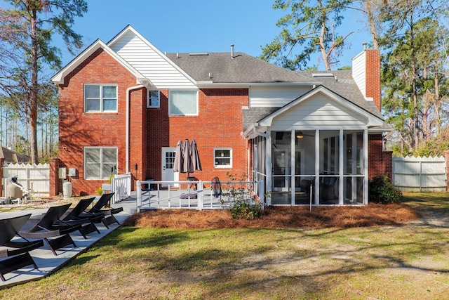 back of house featuring a yard, a patio, a chimney, a sunroom, and fence