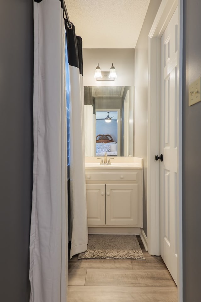 ensuite bathroom featuring a textured ceiling, connected bathroom, wood finished floors, and vanity