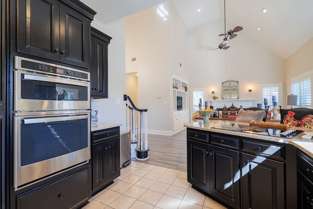 kitchen with light tile patterned floors, double oven, open floor plan, and dark cabinetry