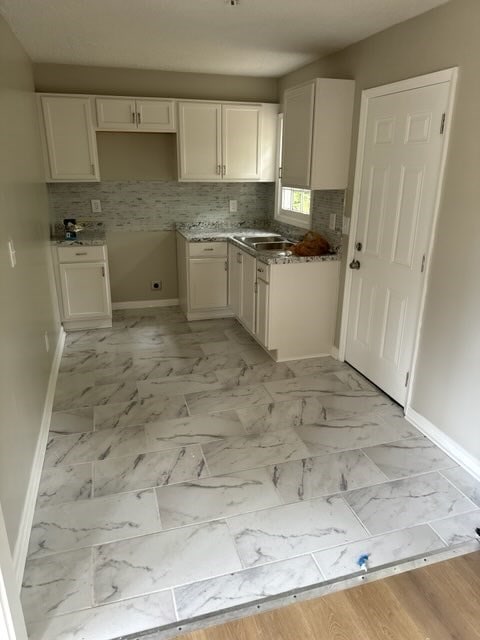 kitchen with backsplash and white cabinetry