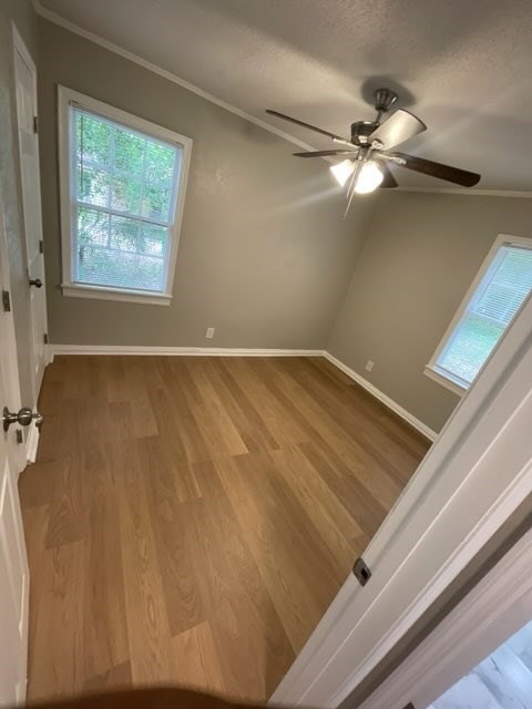 empty room with a textured ceiling, hardwood / wood-style flooring, ceiling fan, and crown molding