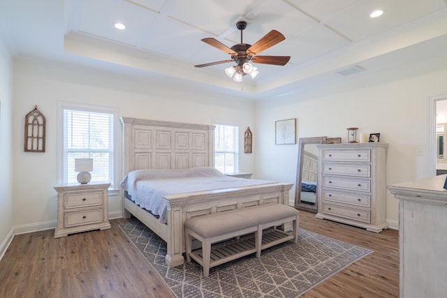 bedroom featuring hardwood / wood-style floors, ceiling fan, a raised ceiling, and crown molding