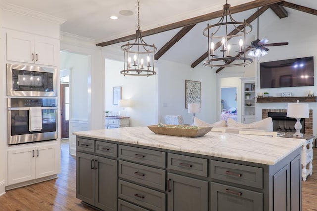 kitchen with vaulted ceiling with beams, a kitchen island, stainless steel appliances, and decorative light fixtures