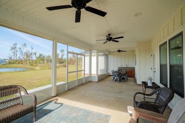 sunroom featuring a water view and ceiling fan