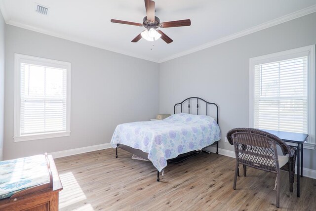 bedroom featuring ceiling fan, ornamental molding, light hardwood / wood-style flooring, and multiple windows