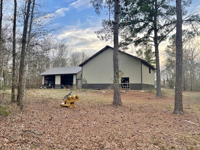 view of property exterior featuring a pole building, a carport, and an outbuilding