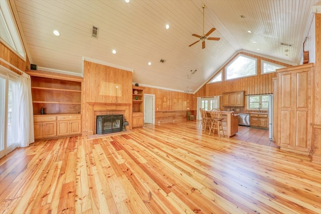 8262 Troupeville Rd, Valdosta, GA 31602 - unfurnished living room featuring light wood finished floors, wooden walls, lofted ceiling, a ceiling fan, and a high end fireplace