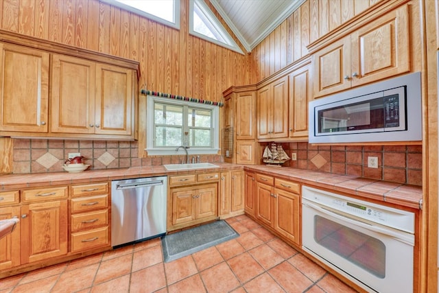 8262 Troupeville Rd, Valdosta, GA 31602 - kitchen featuring stainless steel appliances, a sink, backsplash, vaulted ceiling, and tile counters