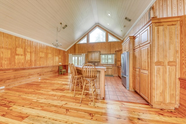 8262 Troupeville Rd, Valdosta, GA 31602 - kitchen featuring freestanding refrigerator, lofted ceiling, a kitchen breakfast bar, light wood-type flooring, and wooden walls