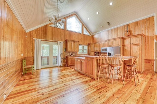 8262 Troupeville Rd, Valdosta, GA 31602 - kitchen featuring appliances with stainless steel finishes, wooden walls, light wood-style flooring, light countertops, and a chandelier