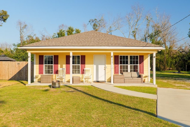 view of front of house with covered porch, a front lawn, a shingled roof, and fence