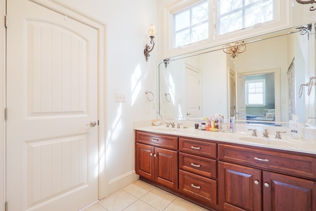 ensuite bathroom with a sink, ensuite bathroom, tile patterned floors, and double vanity