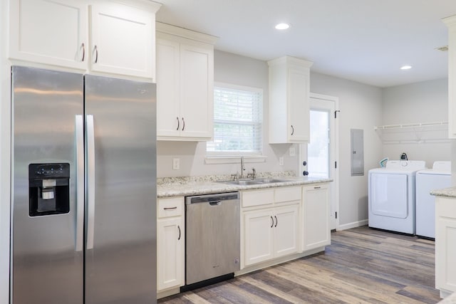 kitchen with sink, dark wood-type flooring, stainless steel appliances, independent washer and dryer, and white cabinets