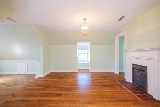 unfurnished living room featuring visible vents, a fireplace, baseboards, and wood finished floors