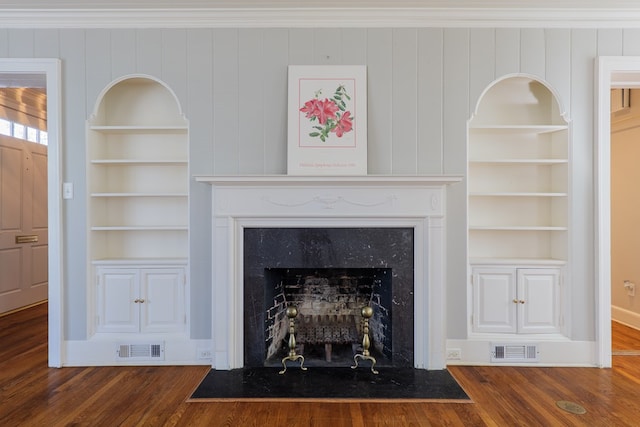 interior details featuring built in features, visible vents, a fireplace, and wood finished floors