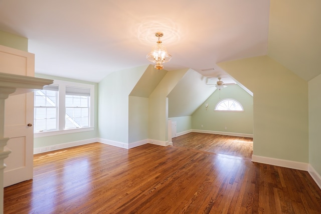 bonus room with lofted ceiling, ceiling fan with notable chandelier, wood finished floors, and baseboards