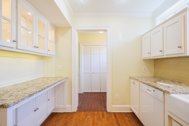 kitchen with light wood-style flooring, decorative backsplash, ornamental molding, glass insert cabinets, and white dishwasher