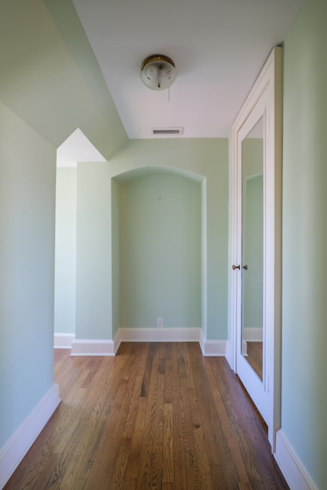 corridor featuring wood finished floors, visible vents, and baseboards