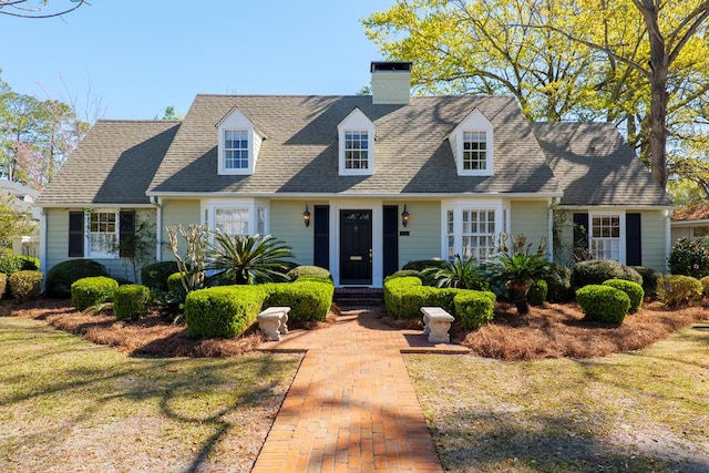 cape cod house with a shingled roof and a front yard