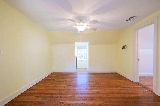 empty room featuring ceiling fan, lofted ceiling, dark wood-type flooring, visible vents, and baseboards