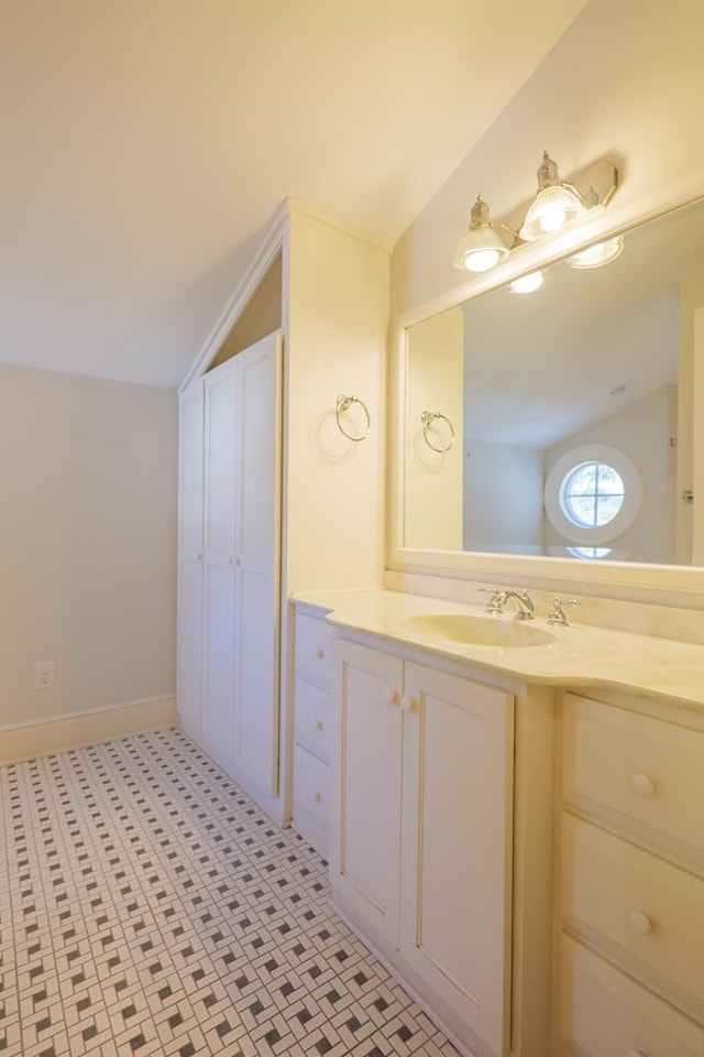 bathroom featuring vaulted ceiling, vanity, and baseboards