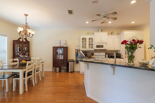 4311 Mossy Creek Rd, Valdosta, GA 31602 - kitchen with white appliances, a chandelier, crown molding, a breakfast bar, and white cabinets