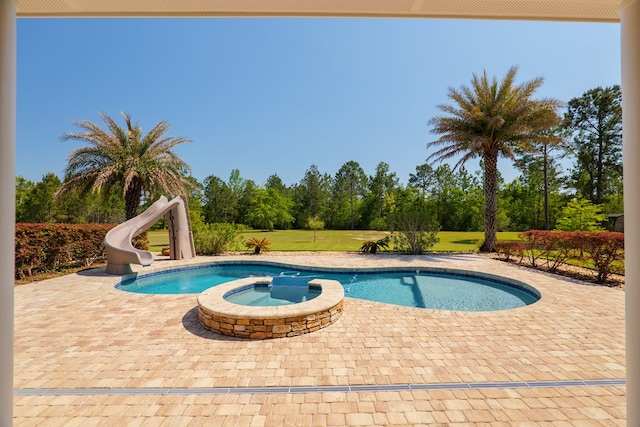 view of swimming pool featuring a water slide, a patio, and a pool with connected hot tub