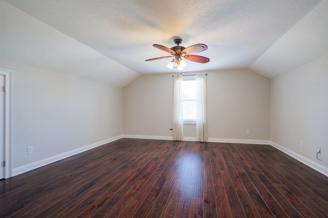 additional living space featuring dark wood finished floors, vaulted ceiling, baseboards, a textured ceiling, and ceiling fan