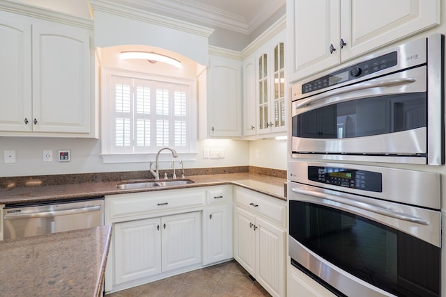 kitchen with a sink, glass insert cabinets, appliances with stainless steel finishes, white cabinets, and ornamental molding