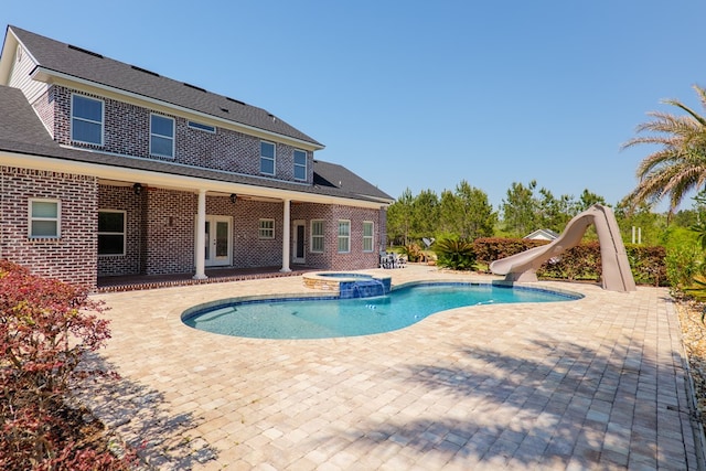 view of pool with a patio area, a water slide, and a pool with connected hot tub