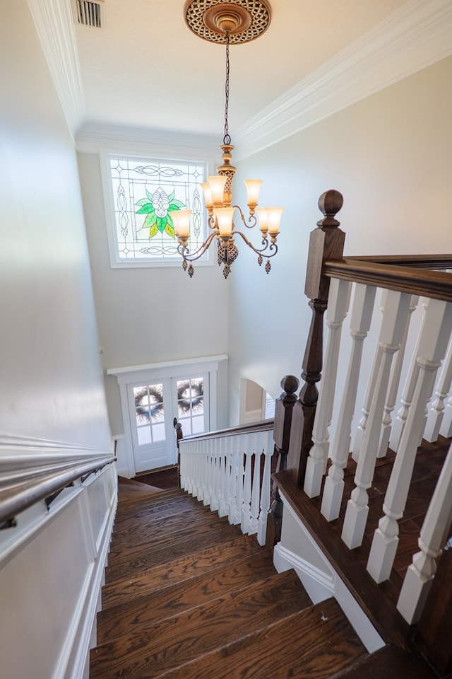 staircase with wood finished floors, visible vents, ornamental molding, french doors, and a notable chandelier