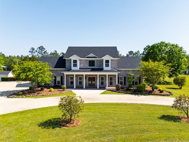 view of front of property with a front lawn, covered porch, and curved driveway