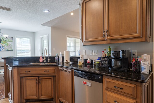 2783 Rabbit Ridge Run, Valdosta, GA 31605 - kitchen featuring stainless steel dishwasher, brown cabinetry, a peninsula, a textured ceiling, and dark stone countertops