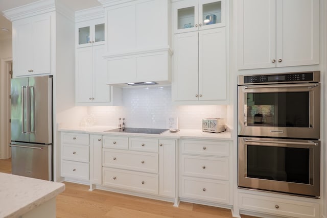 3870 Timber Ridge Rd, Valdosta, GA 31601 - kitchen with appliances with stainless steel finishes, light wood-style flooring, tasteful backsplash, white cabinets, and glass insert cabinets