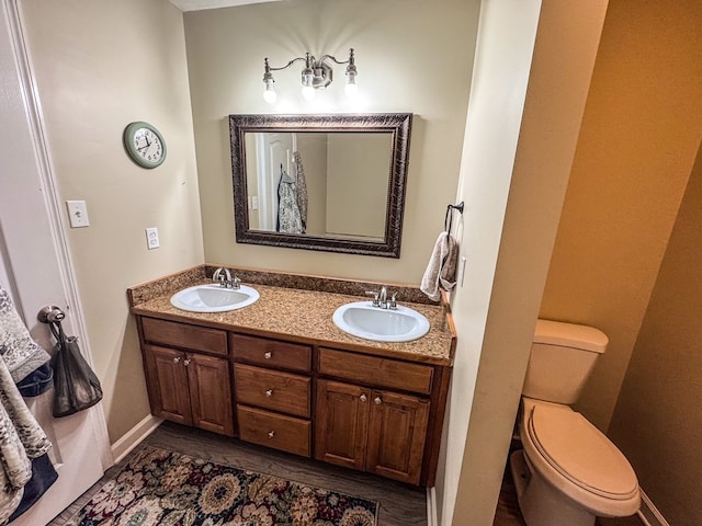 bathroom featuring double vanity, a sink, and toilet