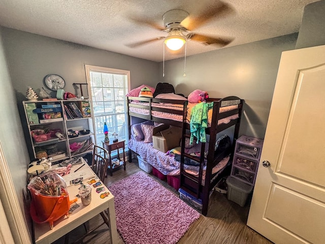 bedroom with a textured ceiling, a ceiling fan, and wood finished floors