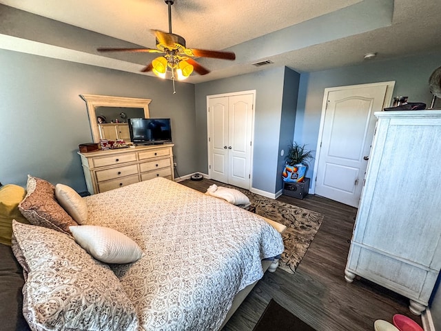 bedroom featuring a textured ceiling, wood finished floors, visible vents, baseboards, and a closet