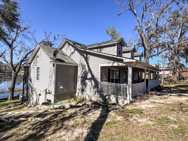 view of side of property with covered porch and a water view