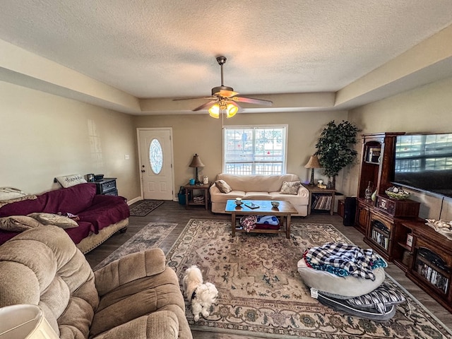 living area with a textured ceiling, wood finished floors, a ceiling fan, and baseboards