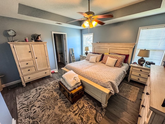 bedroom with baseboards, a textured ceiling, visible vents, and dark wood-type flooring