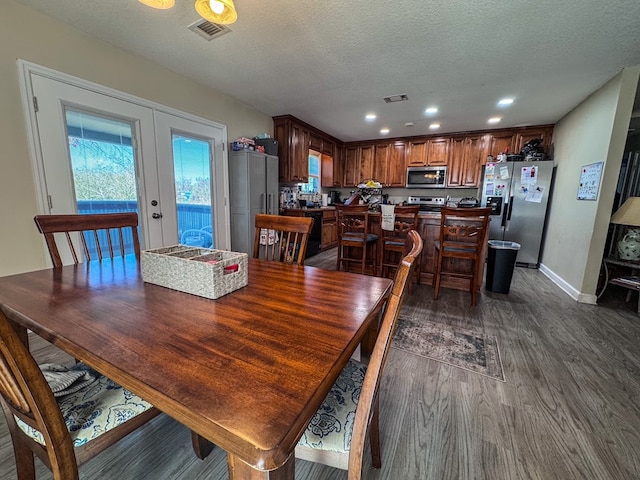 dining area with a textured ceiling, french doors, dark wood finished floors, and visible vents