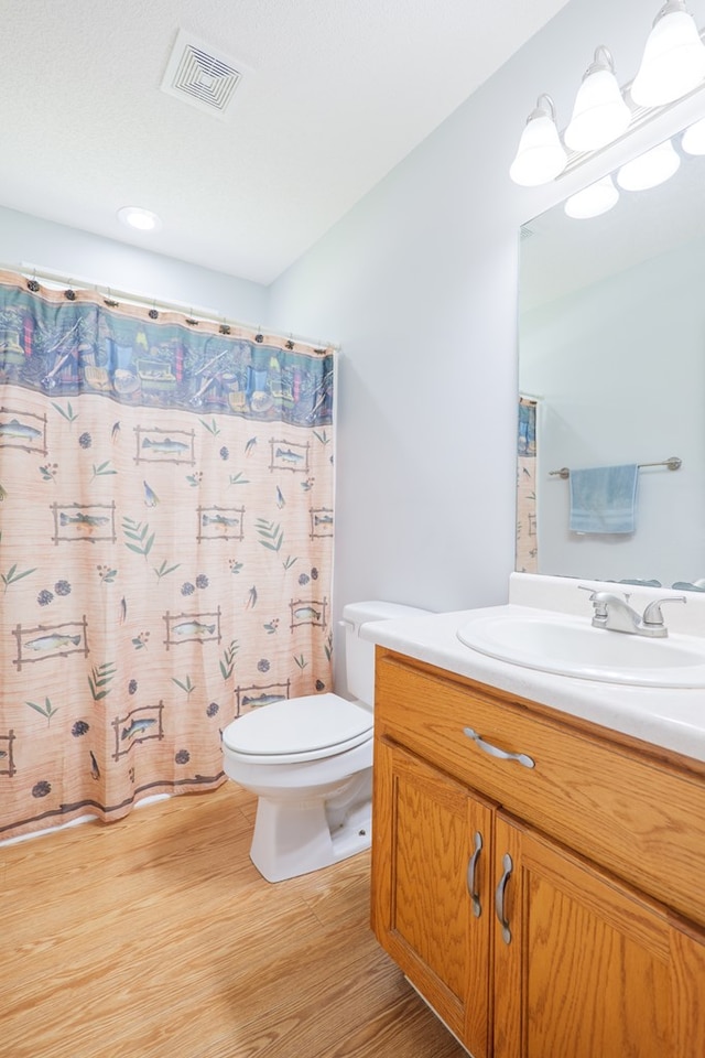 full bath with visible vents, curtained shower, wood finished floors, vanity, and toilet